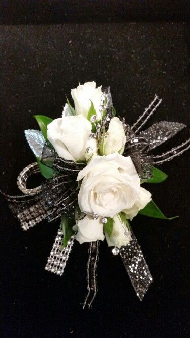 White spray roses with black and silver accents Black White And Silver Corsage, White Corsage With Black Ribbon, White And Silver Corsage And Boutonniere, Black And Silver Corsage And Boutonniere, Black And White Corsage And Boutonniere, White And Black Corsage, Black Corsage Prom, White And Silver Corsage, Silver Corsage And Boutonniere