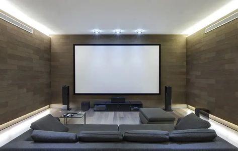 A small modern home theater is perfect as a casual living room feel. Walls are finished with light mocha color stone tile, adding a textured and patterned surface. Wood laminated floors equal to the size as the stone tiles on the walls, adds a continuous pattern throughout. A large projector screen is on the wall and a  low-profile media console at the bottom. The furniture is a simple brown sofa with matching bench and a small black side table. Movie Room Furniture, Small Movie Room, Media Room Furniture, Home Theater Lighting, Media Room Seating, Home Theater Room Design, Theater Room Design, Media Room Design, Theater Design