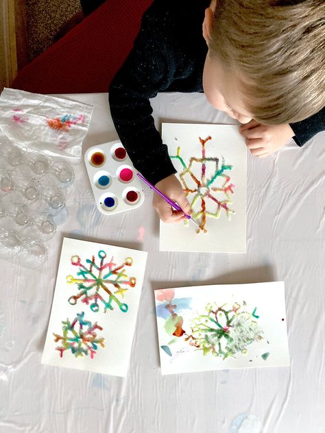 A child is painting a salt snowflake with watercolor paints. Salt Painting Snowflakes, Snowflake Art Project, Watercolor Salt Snowflakes, Winter Magic Watercolor Craft, Magic Salt And Watercolor Snowflake, Printable Snowflake Template, Unique Art Projects, Snowflakes Art, Snowflake Template