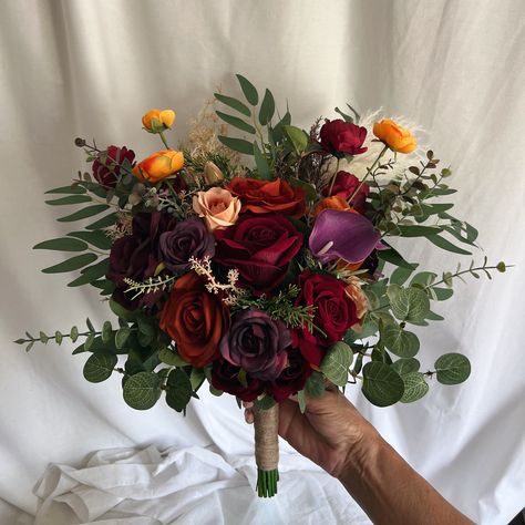 This beautiful artificial wedding bouquet is made from faux flowers of burgundy, terracotta, rust orange, light cream and faux sage greenery, ferns and silk leaves. They will make the perfect addition to your big day!  This bridal bouquet consists of dahlias, roses, peonies and hydrangeas with silk ruscus and sage greenery and fillers. The stems are wrapped in twine. The bridal bouquet pictured is 16" (41 cm). Bridesmaids Bouquets is 9". Matching bridesmaids bouquets, toss bouquet, corsages and boutonnières and other accessories are available. Red And Purple Bridal Bouquet, Dark Purple And Cream Wedding, Burgundy And Purple Wedding, Purple And Orange Bouquet, Orange And Purple Wedding, Purple Terracotta, Purple Bridesmaid Bouquets, Orange Bouquet, Toss Bouquet