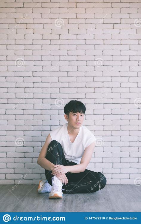 Photo about Asian model man in black pants and white shirt sitting on floor and knee up, photo shot on white bricks wall background. Image of adult, concept, asia - 147572210 Man Sitting On The Floor Reference, Man Sitting On Floor Pose Reference, Guy Sitting Side View, Sitting Reference Pose Floor, Guy Sitting On Floor, Man Sitting On Floor, Sitting Photography, Guy Sitting, White Bricks