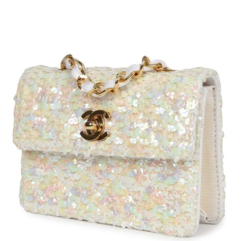 This Vintage micro half flap bag quilted iridescent ivory sequin and ribbed satin with gold hardware, features tonal stitching, cc turnlock closure, interwoven gold tone chain link and white canvas fabric crossbody/shoulder strap.The interior is lined in ribbed ivory satin fabric.Collection: 1-series (1989-1991)Origin: FranceCondition: Vintage; Excellent to Mint - This bag retains its shape and structure. The exterior shows some minor signs of wear with a few loose threads and sequins. The hardware has light scratching. The interior fabric is slightly discolored on interior base but all around clean and date stamp sticker still intact.Accompanied by: Chanel dustbagMeasurements: 5.5" width x 4" height x 1" depth; 21" strap drop Sparkly Designer Bags, White Chanel Bag, Vintage Chanel Bag, Dream Bags, Sequin Bag, Luxury Purses, Chanel Vintage, Pretty Bags, Gold Sequins