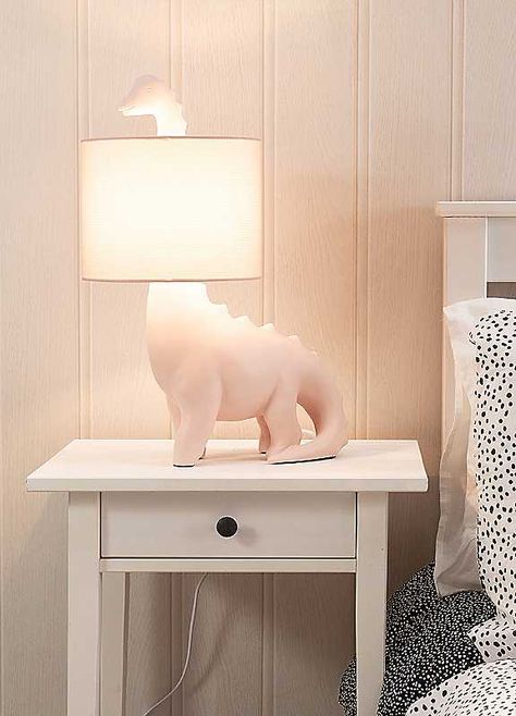 Brighten up your little ones space with this dinosaur shaped table lamp. The ceramic base comes in a pink or green finish with a matching braided flex and fabric drum shade. Give your child's bedroom a pop of colour in a subtle and fun way. The in-line rocker switch provides convenient control, making it easy to illuminate your space. Help your child overcome the fear of darkness and create a comfortable sleep environment with this playful lamp. Brand: ValueLights Ceramic Dimensions approx. 26 x Girly Dinosaur Room, Pink Dinosaur Nursery, Girls Dinosaur Bedroom, Pink And Green Room Decor, Girl Dinosaur Room, Girls Dinosaur Room, Dinosaur Bedroom Ideas, Dinosaur Themed Bedroom, Dino Lamp