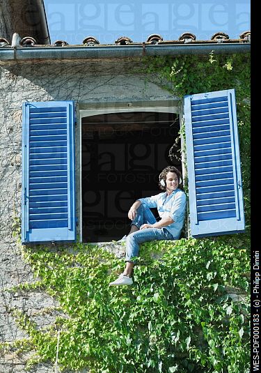 Italy, Tuscany, Young man sitting on window sill with shutters Person Sketching, Sitting On Window Sill, Sitting On Window, Arched Cabin, Window Drawing, Italy Tuscany, Summer Painting, Body Reference Drawing, Sitting Poses