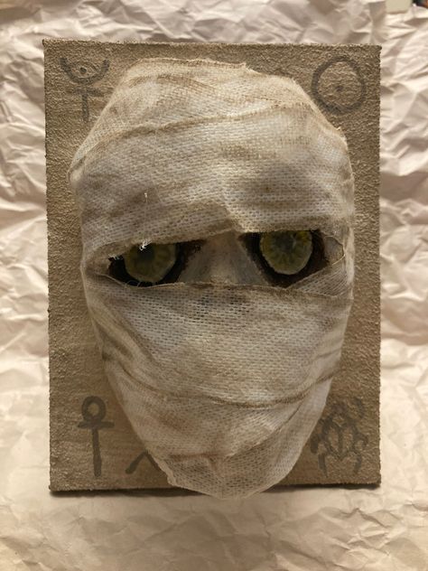 "The Mummy collection. Awake after sleeping for centuries! Glassy eyed Egyptian Mummy Mini Mask has been hand sculpted using my own DIY paper mache clay and recycled paper. Painted with Acrylic paint and sealed with Mod Podge. Mounted on hand painted canvas. Gauze tape for wrappings. Wall mount for easy hanging Recommend NOT getting the mini mask wet, will compromise the structure of the mask. Glassy eyed Egyptian Mummy Mini Mask is 4.5\" x 6.5\" on an 8\" x 6\" canvas. All mini masks are made with recycled paper and DIY environmentally friendly Mexican-style paper mache clay. Every mask is handmade and hand-painted, so each one is unique. May consider a made-to-order Glassy eyed Egyptian Mummy Mini Mask, but be aware of this: I didn't use a mold to create this, so a made-to-order will not Fashion Mask Design, Masks Paper Mache, Mummy Decorations, Diy Paper Mache, Egyptian Mummy, Egyptian Painting, Paper Mache Mask, Making Paper Mache, Paper Mache Clay