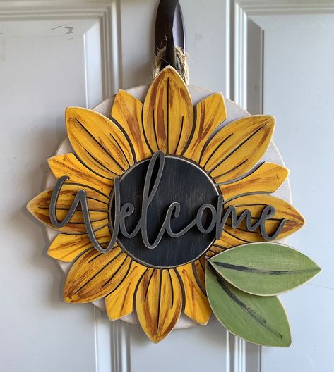 "Handmade with individually painted pieces, this sunflower sign is a sweet way to welcome guests to your home.  It's 14\" in diameter and 1/2\" thick at is thickest part. Handmade in Dubuque, Iowa." Sunflower Door Hanger, Door Signs Diy, Front Door Sign, Wooden Door Design, Farmhouse Style Sign, Handmade Signs, Front Door Signs, Wooden Door Hangers, Sunflower Decor