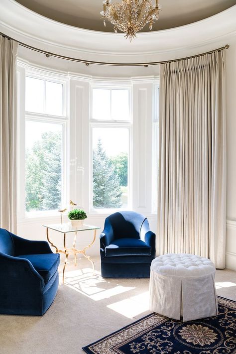 We installed curved rods to compliment the design details in the sitting area of the bedroom. Neutral drapes keep the lighting flattering and inviting. @schonbek @fabricut @schumacher1889 @erinkonrathphotography #afreshtakeonclassicdesign #colleenmcnallyinteriors #freshtraditional #interiordesign #classicdesign #interiorspaces #custominteriordesign #performancevelvet #schustagram #fabricutfind Curved Window Treatments, Neutral Drapes, Masculine Color Schemes, Turret Room, Bedroom Neutral, Mission House, Design Window, Curtain Headings, Custom Window Treatments