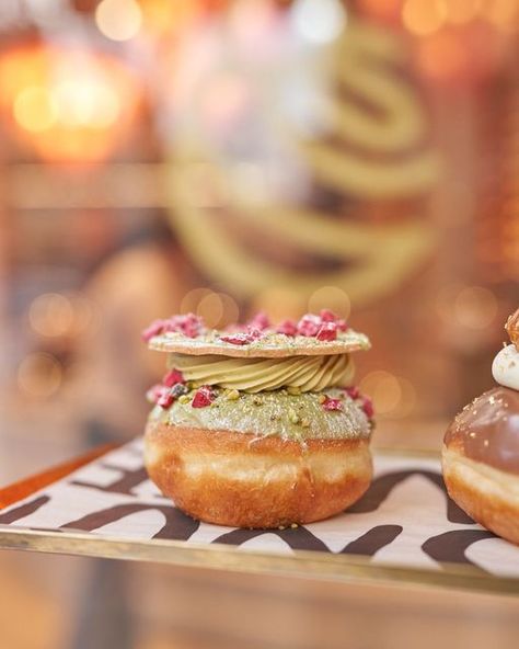 Donutelier by Roladin on Instagram: "Delicately created by our talented chefs, our Pistachio doughnut is filled with Chantilly cream, pistachio varigato and sandwiched by an almond sable! To finish, we sprinkle with a generous helping of almond nibs and crispy raspberry flakes 💚" Donut Plating, Pistachio Doughnut, Raspberry Flakes, Almond Donut, Pistachio Donut, Doughnuts Photography, Super Donut, Donut Filling, Chantilly Cream