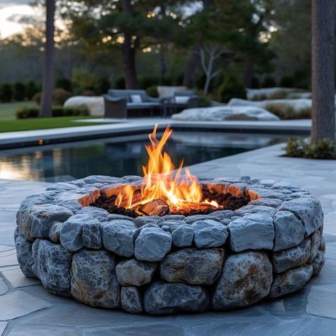 Cozy fire pit on stone patio at sunset, friends and family gathering around the lively flames, swimming pool reflecting the evening sky. Ideal outdoor setting for relaxation and conversation. Fire Pit Next To Pool, Cozy Fire Pit, Outdoor Sanctuary, Stone Patio, Fire Pit Designs, Patio Stones, Fire Pit, Swimming Pool, Swimming Pools