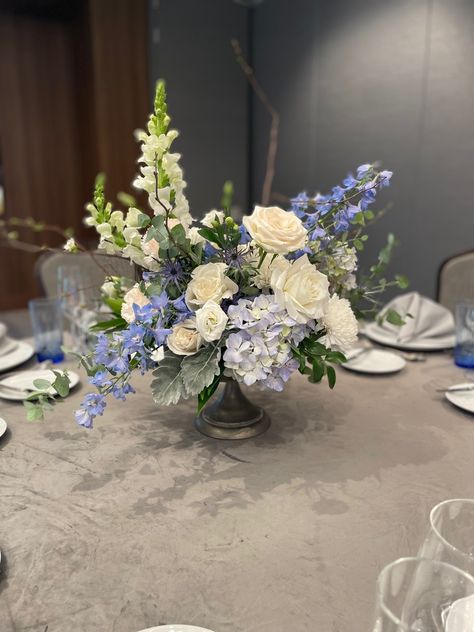 Wedding centerpiece inspiration with elegant hints of blue/purple throughout! Hydrangea And Delphinium Centerpiece, Blue And Green Centerpieces Wedding, Centerpieces Wedding Blue And White, Blue Green Flower Arrangements, Graduation Party Floral Centerpieces, Coastal Centerpiece Ideas Wedding, Blue And White Flower Centerpieces, Blue Centerpieces Wedding, Purple Floral Centerpieces