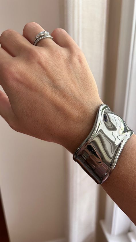 A photo of a white woman’s wrist by a window. She is wearing a wide, sculptural cuff bracelet in ruthenium, a dark silver metal, and two diamond rings on her ring finger. Tiffany And Co Silver Jewelry, Tiffany Bone Cuff Outfit, Tiffany And Co Jewelry Aesthetic, Tiffany Cuff Bracelet, Bone Bracelet Tiffany, Bone Cuff Elsa Peretti, Tiffany Bone Cuff Bracelet, Tiffany Bone Cuff, Mixing Jewelry