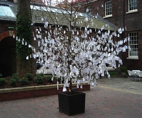 One of the most compelling trees we’ve seen in a public space is Yoko Ono‘s Wish Tree, versions of which have been installed around the world. She conceived of the idea in 1996 – though it’s actually an a very old practice – and it continues to reverberate. People are invited to write their wish on a paper tag and tie it to the tree. It can be done with any tree, anywhere, with any group of people. It’s much more powerful than a wishing well, maybe because you can read other people’s wishes. Wishing Tree Wedding, Text Based Art, Wish Tree, Light Up Tree, Memory Projects, Tree Tags, Wishing Tree, Tree Base, People Tree