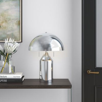 This 2-light table lamp delivers modern materials and a sleek silhouette. It's made from metal with a neutral-hued metallic finish, and it stands on a cylindrical base that extends into a dome shape, topped with a dome-like shade. This lamp accommodates two 60W bulbs (sold separately), that each turn on and off with the two included pull chains. With its vintage-inspired details and futuristic look, this lamp blends the old and the new for a fresh yet versatile aesthetic. Finish: Brushed Nickel Sideboard Decor, Silver Table Lamps, Silver Lamp, Chrome Lamp, Metal Lamp Shade, Side Lamps, Metal Table Lamp, The Embrace, Metal Table Lamps