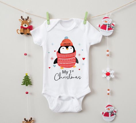 Personalised Baby Penguin Babygrow/Sleepsuit - First Christmas Our Personalised Baby Penguin Babygrow/Sleepsuits are an essential outfit for your little one's First Christmas, what else are they going to wear on Christmas Day? Featuring an adorable penguin in a kntted red jumper, this babygrow/sleepsuit will be sure to bring a smile to peoples faces this Christmas. Please note that 'My 1st Christmas' is fixed text, please add the name of your choice to be printed in the hat. All our designs are Peoples Faces, Onesie Ideas, Christening Present, Spelling Mistakes, Christmas Cricut, Christmas Bodysuit, Red Jumper, Christmas Onesie, Family Shirts Matching