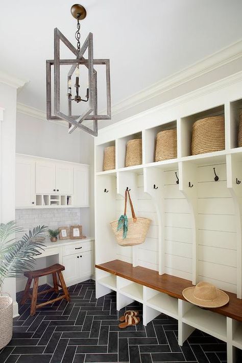 Spacious mudroom features white lockers with oil rubbed bronze hooks mounted on shiplap trim, cubbies with round woven bins, a built in bench, a white built in desk under white cabinets and a wooden stool on black herringbone floors. Black Herringbone Floor, Black Herringbone Tile, Shiplap Trim, Wood Lockers, Gray Shiplap, Transitional Laundry Room, Mudroom Remodel, Mudroom Lockers, Grey Floor Tiles