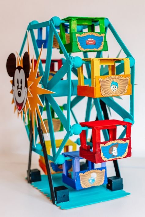 How To Make A Popsicle Stick Ferris Wheel (+ Pixar Pal-A-Round!) | studiodiy.com Popsicle Stick Ferris Wheel, Circus Bedroom, Wheel Crafts, Disney Christmas Village, Popsicle Stick Houses, Disneyland Birthday, Disney Diy Crafts, Wheel Craft, Christmas Village Accessories