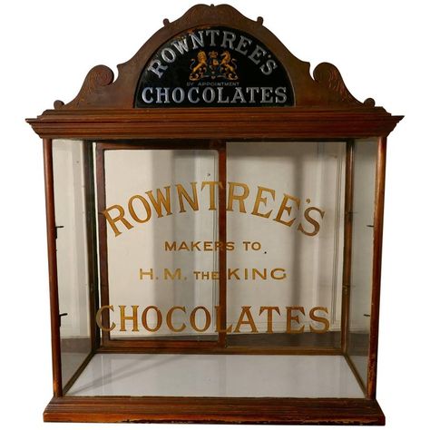 Rountree’s Sweet Shop Display Cabinet This glazed advertising Shop Display Cabinet is made in mahogany, the cabinet has a rather grand carved cornice with a mirrored Royal Appointment sign and Chocolates in Gold and Silver The Glass on the front of the cabinet is painted and etched with Rowntree’s Chocolates Makers to H.M. the King The cabinet has 2 plate glass shelves and a pair of sliding doors at the back This is a very attractive piece, it is in reasonably good condition, it would be wonderf Sweet Shop Display, Old Fashioned Sweet Shop, Antique Display Cabinets, Store Advertising, Decor Shelves, Kisses Candy, Pro Art, Antique Advertising, Shop Cabinets