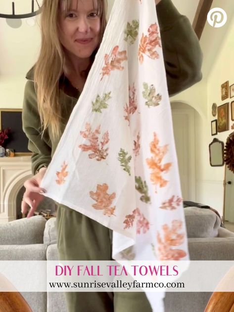 A woman holding up a white tea towel decorated with orange and green leaf prints. The bottom text reads "DIY Fall Tea Towels" with a link to sunrisevalleyfarmco.com. Handprint Towels, Painted Tea Towels, Tea Towel Diy, Diy Tea Towels, Tea Towels Crafts, Kitchen Towels Crafts, Tea Towels Diy, Diy Tea, Diy Mural