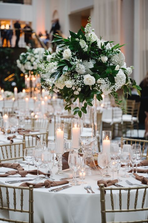 Lush and a-symmetric white and green wedding centerpiece atop a tall clear glass vase with candles to surround. PC: Asya Photography https://asyaphotography.com/ White And Green Wedding Flowers Table Centerpieces, Ivory Centerpieces, White Wedding Arrangements, Tall Flower Centerpieces, Green And White Wedding Flowers, Green Wedding Centerpieces, Centrepiece Ideas, Glass House Wedding, White And Green Wedding