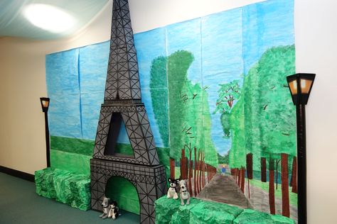 Our office decorated for Party Day theme of Paris! Mural hand painted by my colleagues. The Eiffel Tower constructed from cardboard boxes, paint and black tape. Hedges are boxes covered in painted crumpled paper. Lamp posts made from poster tubes. Paris Theme Classroom, France Themed Party, Around The World Prom Theme, Paris Prom Theme, Mural Hand Painted, Airport Theme, Travel Theme Classroom, Paris Crafts, Paris Prom