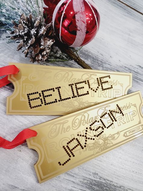 "We are so excited to share these new personalized ornaments with you! Polar express ornament personalized train ticket Christmas ornament polar express train ticket gold believe magic acrylic ornament We engrave gold acrylic ornament with your choice  and punch out the personalized name or word of your choosing they are then hung red ribbon to easily add to your tree or Christmas stocking. Choose from either \"BELIEVE\" or your Childs name to be cut out as if it were hole punched! Tags ornaments are 6inches x 2.5 inches to provide a perfect size ornament or stocking tag.  These ornaments are sure to add to your Christmas magic this year and for years to come. please note the back of these are black due to the fact they are made from mirror acrylic" Polar Express Theme Tree, The Polar Express Christmas Decorations, Diy Train Ornaments, Diy Polar Express Ticket, Polar Express Golden Ticket Printable, Polar Express Themed Christmas Tree, Polar Express Theme Christmas Tree, Polar Express Decorations Diy, Polar Express Christmas Party Decoration