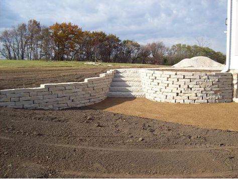 This white brick retaining wall with the stone steps is a good choice. Choosing a neutral color like this would be a great way to ensure that it will match your home. I've always liked retaining walls, especially since they can improve your home's design while also holding back dirt so that your landscape looks the way you want. White Stone Retaining Wall, White Retaining Wall, Retaining Wall Bricks, Retaining Wall Block, Lime Wash Brick, Garden Spheres, Stone Retaining Wall, Outdoor Stone, Gate House