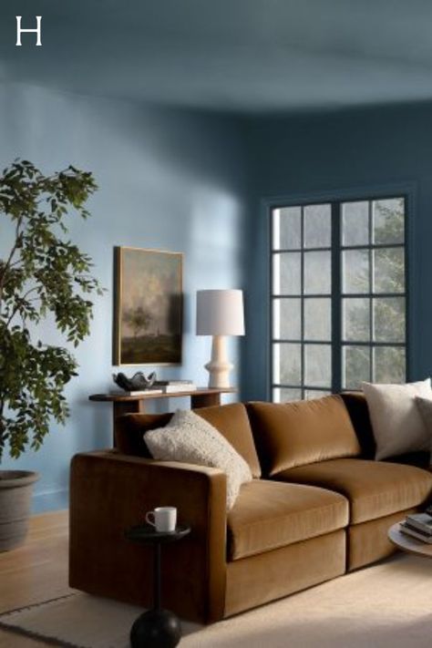 Dark brown couch living room ideas don’t have to rely on neutral color palettes — just look how sumptuous a tan velvet sectional from Interior Define looks in a space awash in crisp light blue wall paint. The color pairing may seem unexpected but it works for a reason: They’re hues often found together in nature. Brown Couch With Blue Accents, Light Blue Wall Paint, Blue Brown Living Room, Living Room Ideas Dark, Blue And Brown Living Room, Brown Couch Living Room Ideas, La Bedroom, Blue Wall Paint, Tan Sectional