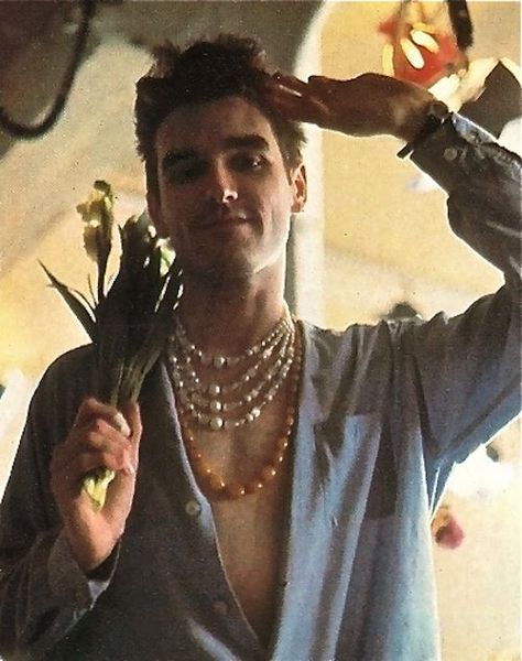 In the early 1980s the Smiths popularized jewelry for men, reviving a hippy trend from the 1960s.  In a then-sexist Britain, it was a bit of a shock to see men wearing ropes of beaded and jewelled necklaces, and even wielding bunches of beautiful flowers in nightclubs and pubs. In the photo Morissey, the band's star, looks great in his layered necklaces! Well done, Morrissey! The Smiths Morrissey, How Soon Is Now, Don Pedro, Johnny Marr, Charming Man, The Smiths, Morrissey, Music Icon, Post Punk