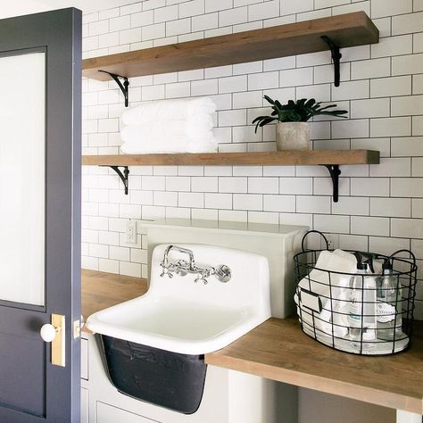 A navy blue door accented with a brass knob opens to a laundry room featuring wood and iron shelves stacked and mounted against white subway backsplash. Colonial Laundry Room, Mud Room Sink, Vintage Bathroom Sink, Cottage Laundry Room, Sink Laundry Room, Fixer Upper Home, Cast Iron Sink, Vintage Sink, Simple Bathroom Decor