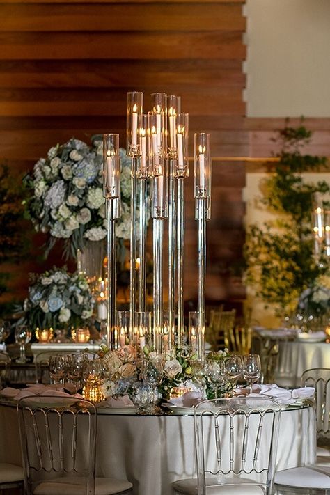 Add a stylish and sophisticated appeal to your event décor with exquisite accessories. Dress up your party tables with chic white tablecloths and match them with white chair pads for a cohesive appeal. Moreover, add dreamy vibes to your setup by lighting up candles secured in clear glass candelabras and beautifying the centerpieces further with lovely white and blush roses. For a presentable place setting, pair white chargers with white napkins and cutlery. 5 Arm Candelabra Wedding Centerpieces, Candelabra Centerpieces, Pillar Candle Decor, Decorative Pillars, Glass Candelabra, Candelabra Centerpiece, Decoration Event, Crystal Candelabra, Elegant Tablecloth