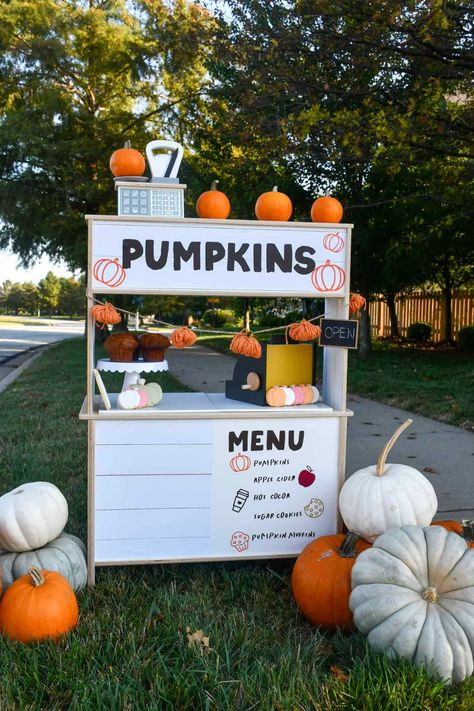 Decorated pumpkin stand made from the Ikea play kitchen. Has toys on it and pumpkins around it. Fall Lemonade Stand, Ikea Duktig Hack, Ikea Duktig Kitchen, Pumpkin Menu, Fall Bake Sale, Apple Cider Cookies, Ikea Garden, Stall Decorations, Diy Lemonade Stand