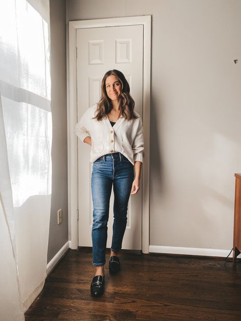 ashley wearing a cream colored button front cardigan buttoned up with a black bodysuit underneath, mid-wash straight leg jeans, and black loafers, standing in front of a white door with a window and sheer white curtain to the side Buttoned Cardigan Outfit, Button Down Cardigan Outfit, Layering Fall Outfits, Button Cardigan Outfit, Ways To Style A Cardigan, Cream Cardigan Outfit, Layering Dresses, Layered Clothes, Style A Cardigan