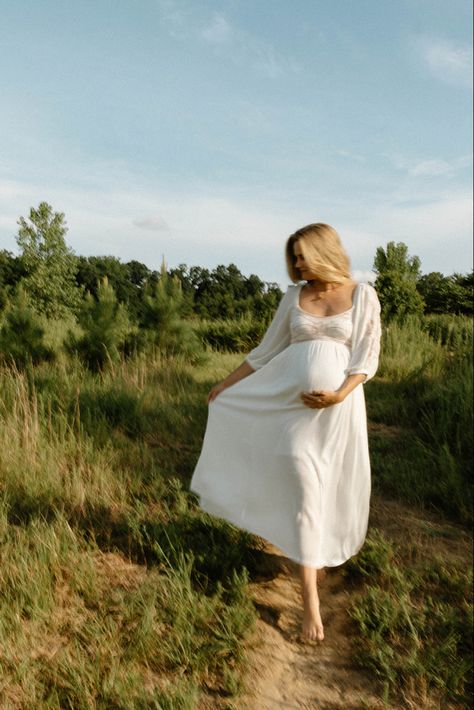 Pregnant mother cradles her baby and she walks down a dirty path in an open field in a white flowy dress Maternity Film Photos, Modern Maternity Shoot, Pregnancy Film Photography, Cinematic Maternity Photography, Film Maternity Photography, Documentary Maternity Shoot, Documentary Maternity Photography, Maternity Photography On Film, Documentary Style Maternity Photos