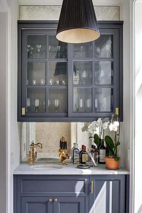 This gorgeous dark gray wet bar boasts sliding glass dark gray cabinets fitted with brass inset hardware and mounted to an antique mirrored backsplash. Gray Wet Bar, Mirrored Backsplash, Kitchen Wet Bar, Bar Nook, Vintage Faucet, Kitchen Bar Design, Home Wet Bar, Refacing Kitchen Cabinets, Bar Vintage