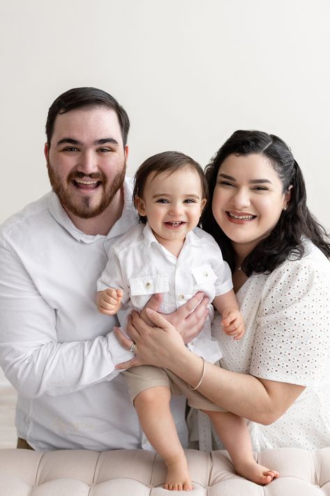 Family first birthday photo of a happy one-year-old boy as he stands on a tufted bench between his parents taken next to a window streaming natural light in a studio near Kirkwood in Atlanta, Georgia by Lily Sophia Photography. 1st Birthday Photoshoot With Parents, Family Potrait, Baby Family Pictures, First Family Photos, Milestone Photography, First Birthday Photo, 1st Birthday Photoshoot, Natural Light Studio, Expecting A Baby