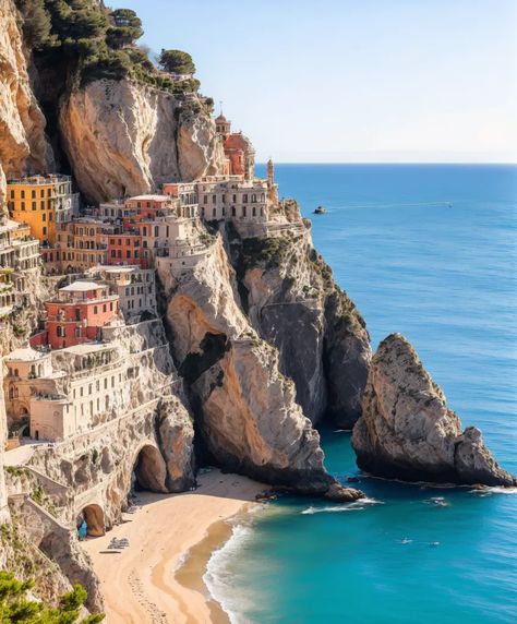 The image shows a beautiful coastal village built on a cliffside. The village is surrounded by sheer cliffs and turquoise blue sea. The houses in the village are built close together and are painted in a variety of colors. The village is accessible by a road that winds its way up the cliffside. There is a small beach at the bottom of the cliff, and a few boats are anchored in the bay. The water is crystal clear and a deep blue color. The sky is blue and there are a few clouds in the House On A Cliff By The Sea, Coastal Village Aesthetic, Coastal City Aesthetic, Cliffside Town, Cliffside Village, Town By The Sea, Seaside Cliff, Cliffside House, Village By The Sea