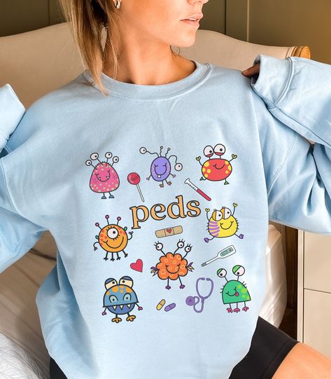 This Pediatrics Department / PEDS Nurse Sweatshirt / Pediatrician Sweatshirt is so cute and perfect for working in Pediatrics! Makes a great gift for the PEDS Nurse or Pediatrician in your life! Makes a great gift or buy for yourself!  **UNISEX SIZING**  See all of our Pediatric items here!:  https://tinyurl.com/mpuwwyjb Click here to return to our shop's home page ⇒ https://www.etsy.com/shop/SketchyCatDesigns ♥ W E L C O M E  T O  S K E T C H Y  C A T  D E S I G N S ! ♥ Click here to return to Peds Nurse Aesthetic, Pediatric Doctor, Nursing Goals, Peds Nurse, Picu Nurse, Pediatric Nurse, Nurse Sweatshirt, Pediatric Nursing, Nurse Shirt