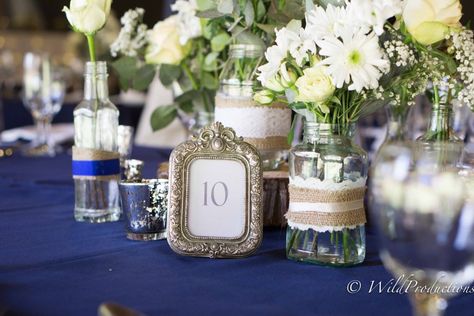 A beautiful rustic wedding with navy blue table cloths, accents in hessian and beige, wrapped around jars and bottles for added interest.  Flowers used are cream and white roses, chrysanths, gypsophila and penny gum. Wedding With Navy Blue, Jean Flowers, Blue Table, Table Cloths, White Table, White Roses, Rustic Wedding, Table Cloth, Penny