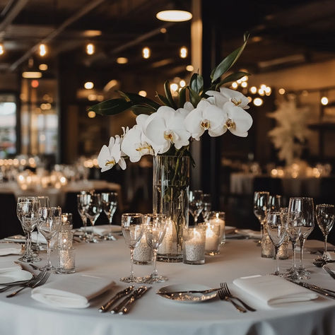 Create a refined and contemporary wedding reception look with this elegant table setup. Featuring a simple yet sophisticated centerpiece of white orchids in a tall glass vase, surrounded by glowing candles and sparkling glassware. This minimalistic design is perfect for modern couples who love understated luxury. Ideal for intimate venues or grand spaces alike. Pin this for minimalist wedding decor inspiration! #ModernWedding #OrchidCenterpiece #ElegantWedding #MinimalistDecor #TableSettingIdeas Wedding Reception Decorations Minimalist, Modern Clean Wedding Decor, Modern Reception Decor, Simple Elegant Wedding Table Decor, Elegant Minimalist Wedding Decor, Floating Candles Wedding Centerpieces, Minimalist Wedding Centerpieces, Minimalist Centerpieces, Modern Wedding Table Decor