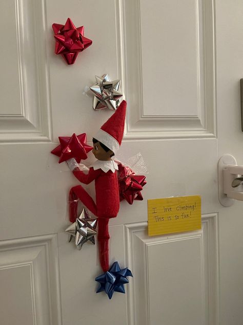 elf on the shelf climbng, elf on the shelf, elf on the shelf gift bows #elfontheshelf #elfontheshelfideas #elfontheshelfideasforkids Elf On The Shelf Bows, Elf On The Shelf Climbing, Elf On The Shelf Gymnastics Ideas, Wire In Elf On The Shelf, Elf On Shelf Streamers, Elf Climbing On Bows, Elf On The Shelf Climbing Bows, Elf On The Shelf Wall Climbing, Elf On The Shelf Bow Climbing Wall