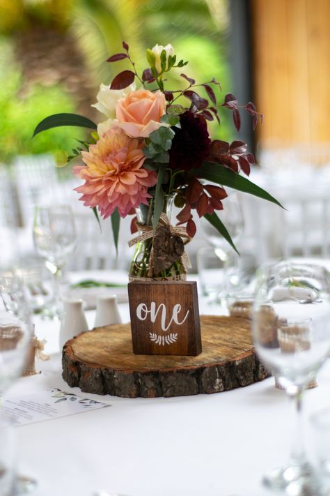 Warm tone flowers in vase on wedding table with log and table one wooden block #wedding #weddinginspiration #weddinginspiration #weddingphotography #centrepiece #weddingtable #weddingtabledecorations #tabledecoration #kumeuvalleyestate #vintagewedding #rusticfeel #farmhousevibe #nzwedding #engaged #married Wood Cookies, Mill Wedding, Log Slice, Rustic Autumn, Flowers In Vase, Table Centrepiece, Warm Tone, Wedding Table Decorations, Centre Piece