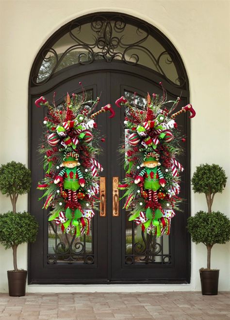 xtra Large Christmas Elf Wreath for Double Doors | Nice Elf Christmas Theme Swag For Front Door | Red, White, Gold Christmas Decor Merry Christmas, Happy Holidays, and a Happy New Years everyone! Introducing a brand new elf swag. This wreath has a large red sparkly bow, made with both red ribbon and white/ green ribbon with a white and black satin pattern in the center. This ribbon is about 4 inches thick. On the top of this swag are various sparkly picks in gold, red and light green to match the elf suit. In the center there are different colored ornaments all red, green, and white. A beautiful stuffed elf man in the center with two reflective gift box ornaments on the side. To match the top, on the bottom is the same red  bow and a different all satin ribbon with the same white, green an Double Door Wreath Ideas Christmas, Christmas Door Decorations Outdoor, Wreaths For Double Front Doors, Elf Christmas Theme, Outdoor Wreaths On House, Double Door Christmas Decor, White Gold Christmas Decor, Front Door Christmas Garland, Red White Gold Christmas