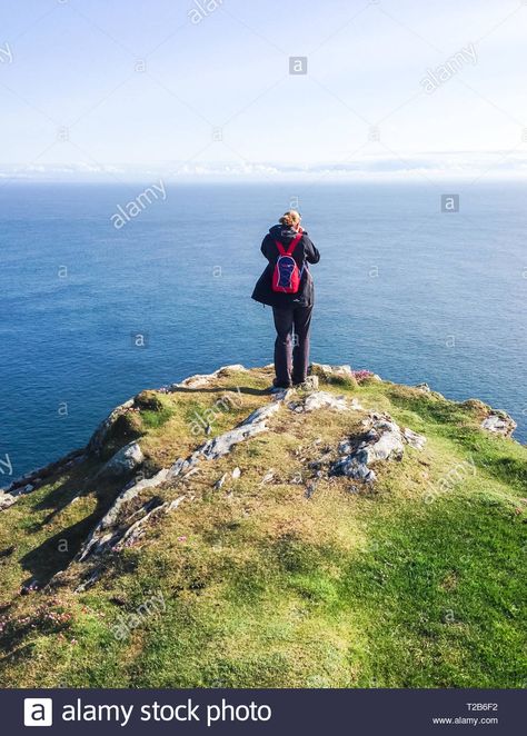 Download this stock image: A hiker with a small red backpack stands on the edge of a cliff overlooking the ocean on a sunny day. Photographed on the tip of the Oa Peninsula on t - T2B6F2 from Alamy's library of millions of high resolution stock photos, illustrations and vectors. Cliff Drawing Reference, Cliff Reference, Cliff Drawing, Standing On A Cliff Drawing, Edge Of A Cliff Drawing, Standing On A Cliff, Person Falling Off Cliff, Cliff Edge Drawing, Sitting On The Edge Of A Cliff