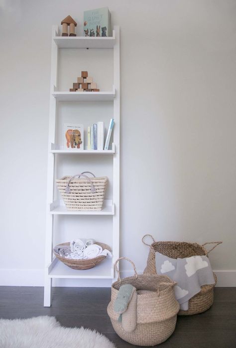 A simple white ladder shelf in a children's room Shelf For Baby Room, Ladder Shelf In Nursery, Book Shelf For Nursery Small Spaces, White Shelf Nursery, Nursery Ladder Shelf, Baby Room Book Shelf Ideas, Cameron Parker, White Ladder Shelf, Amazing Nursery