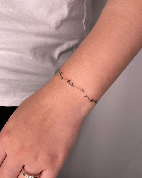 60+ Best Daisy Tattoo Ideas & All You Must Know About Them - InkMatch Daisy Chain Tattoo Small, Daisy Chain Anklet Tattoo, Dainty Flower Chain Tattoo, Daisy Chain Tattoo Wrist, Cute Bracelet Tattoos, Daisy Ring Tattoo, Flower Vine Bracelet Tattoo, Ring Band Tattoo For Women, Constellation Wrap Around Tattoo