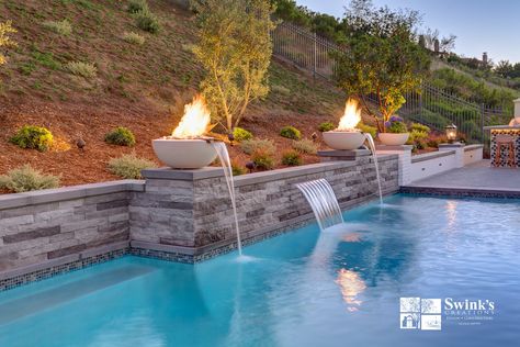 Two 30” round, crème-colored ceramic Outdoor Plus fire and water bowls sit on top of stacked stone raised pilasters, creating a focal point for this pool in Calabasas, CA. Installed on the raised bond beam in between the pilasters is a 36” sheer descent water feature. Fire Feature Pool, Cabana Ideas, Farm Entrance, Florida Pool, Pools Backyard Inground, Covered Patios, Pool Water Features, Pool Renovation, Pool Remodel