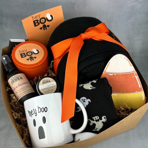 My gift boxes make the perfect gift! Each box measures 10"x10"x6", is tied with a black ribbon and is ready to give as a gift to that special person. Gift box includes: (1) 8 oz natural, hand poured, soy candle in orange tin in your choice of scent (1) custom box of matches (1) 50"x60" black fleece blanket (1) pair of halloween socks (1) halloween 12 oz coffee mug (1) halloween candy corn wooden sign (1) 2 oz linen spray in your choice of scent (1) small pumpkin pie lotion bar (1) custom greetin Gift Basket Ideas Halloween, Halloween Gift Baskets For Adults, Adult Boo Basket, Trick Or Treat Gifts, Halloween Hostess Gifts, Cake Gift Basket, Scary Gift, Boo Baskets, Halloween Gift Baskets