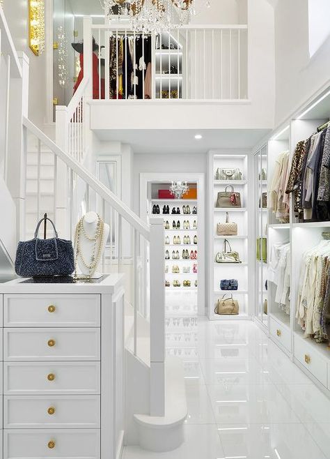 Luxurious 2 story walk-in closet showcases a tall white jewelry dresser placed against an all white staircase. Luxurious Walk In Closet, Placard Design, White Staircase, White Stairs, Walking Closet, White Closet, Dream Closet Design, Walk In Closet Design, Luxury Closets Design