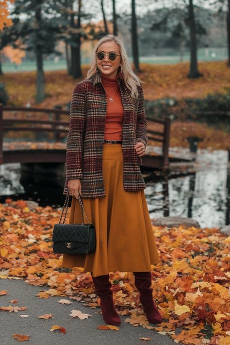 A woman in a fall-inspired outfit wearing a plaid coat, mustard midi skirt, turtleneck, and burgundy boots, carrying a channel  designer handbag while walking through a park surrounded by autumn leaves. Midi Skirt Outfit Winter, Fall Coat Outfit, Boots Long, Burgundy Boots, Chunky Heel Boots, Midi Skirt Outfit, Winter Skirt Outfit, Fall Boots, Varsity Jackets