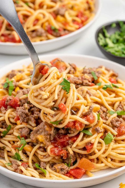 eating Crockpot Taco Spaghetti from a plate using fork.